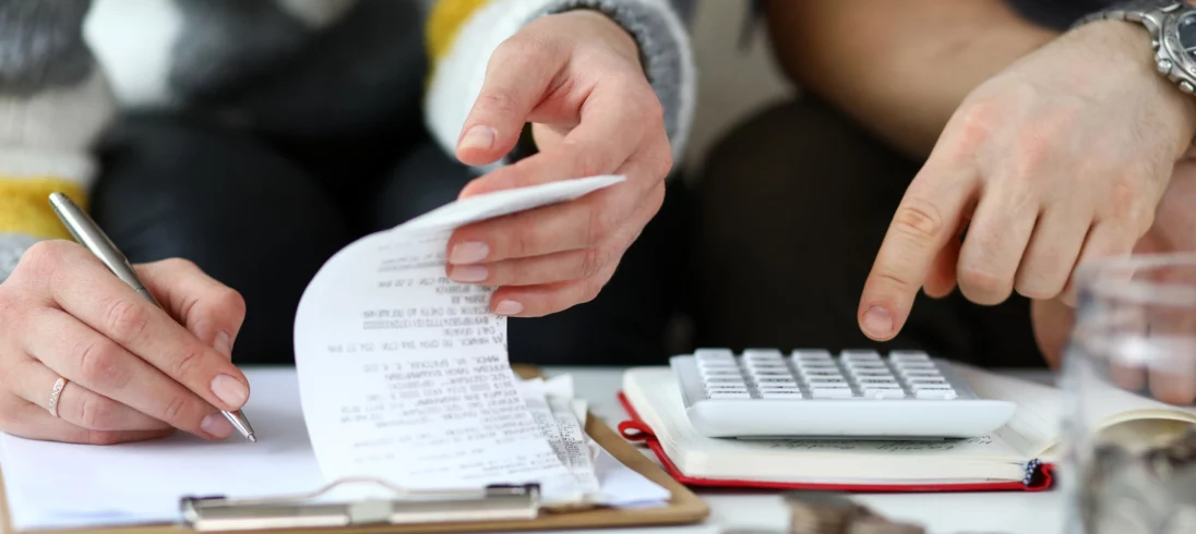 Imagem de um casal fazendo contas com uma calculadora e caderno em cima de uma mesa para ilustrar matéria sobre o que é IPCA