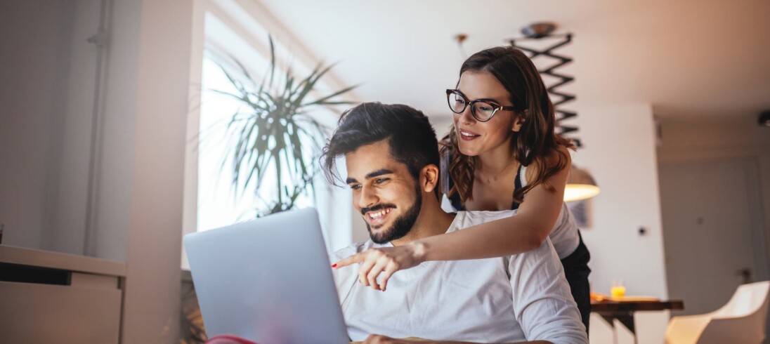 casal sorrindo e olhando o computador