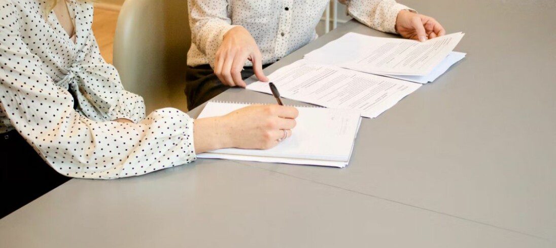 duas pessoas mexendo em papéis em uma mesa ilustrando artigo sobre o que é crédito imobiliário