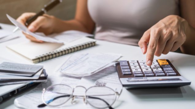 Foto que ilustra matéria sobre preço de aluguel, mostra as mãos de uma mulher em detalhe enquanto ela usa um calculadora.