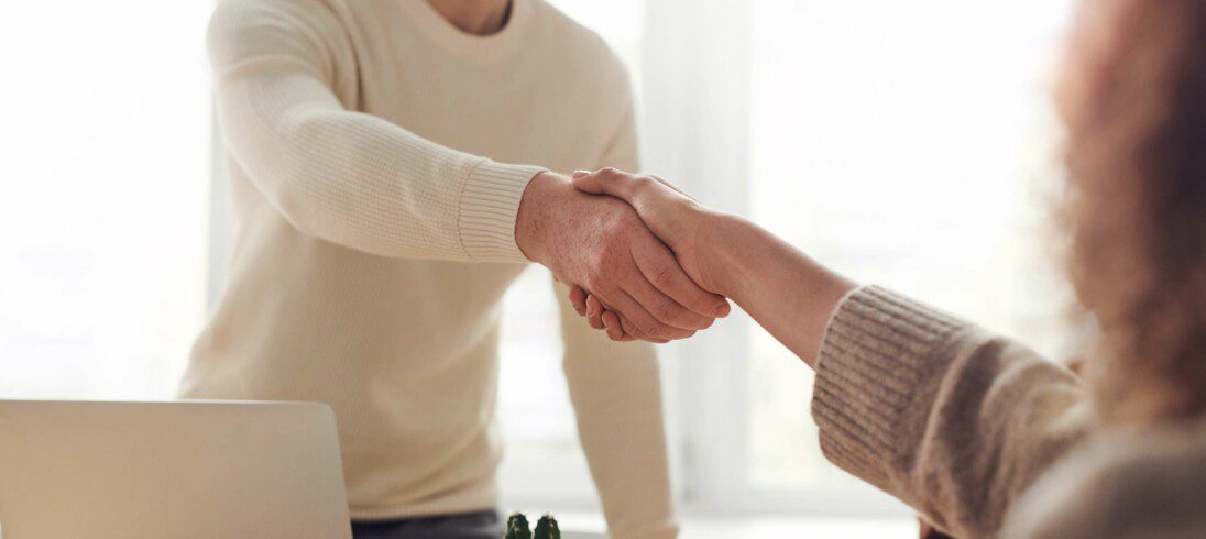 Foto que ilustra matéria sobre como conseguir juros mais baixos para comprar imóvel, com duas pessoas apertando as mãos em sinal de negócio fechado.