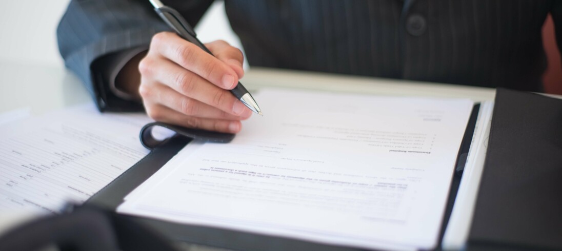 Foto que ilustra matéria sobre título de capitalização de aluguel, com uma pessoa assinando um documento.