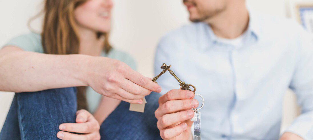 Foto que ilustra matéria sobre aluguel sem fiador, com duas mãos segurando uma chave cada e se tocando.