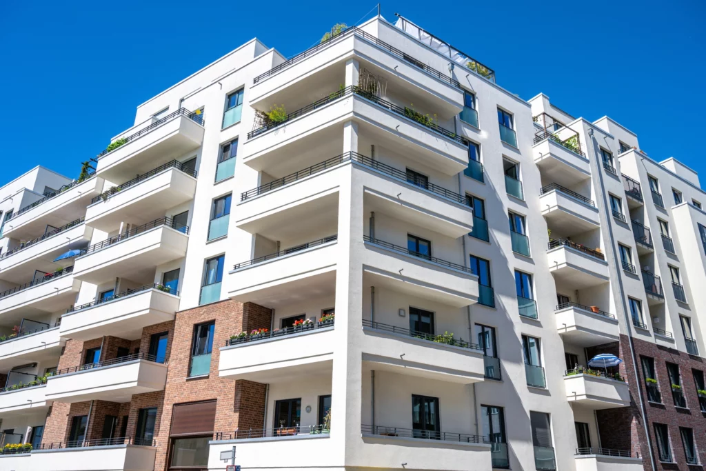 Imagem do lado externo de um edifício residencial branco para ilustrar matéria sobre casa ou apartamento