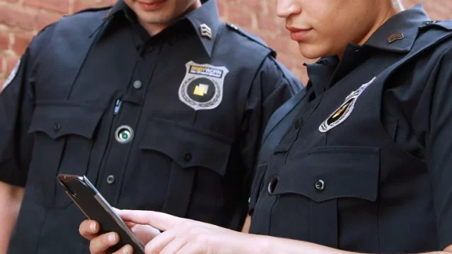Foto que ilustra matéria sobre programa habitacional para agentes de segurança, o Habite Seguro, mostra um policial homem e uma policial mulher olhando para um celular.