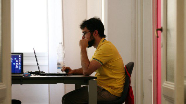 Foto que ilustra matéria sobre mercado de imóveis mostra um homem sentado em uma cadeira de escritório em frente a um computador dentro de um escritório em casa.