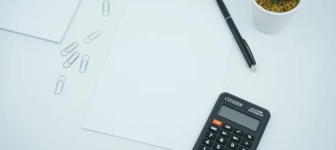 calculadora e caneta sob um papel em uma mesa, ferramentas para calcular correção monetária