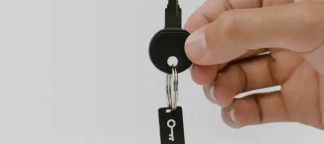 Foto de uma mão segurando uma chave de um imóvel. O chaveiro é um pendrive sinalizando segurança.