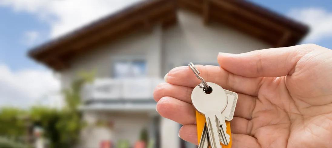 Foto de uma mão segurando as chaves de uma casa.