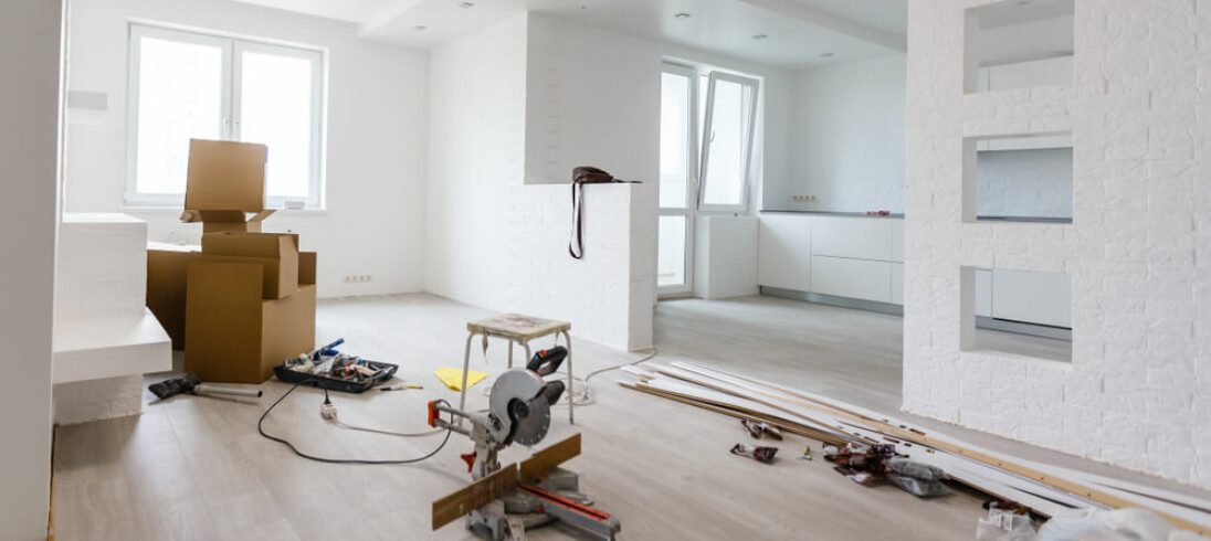 Foto que ilustra matéria sobre quanto custa reformar um apartamento mostra uma sala com algumas caixas, materiais e ferramentas, indicando uma obra.