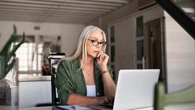 Foto que ilustra matéria sobre planejamento sucessório mostra uma mulher sentada em uma mesa mexendo em um computador