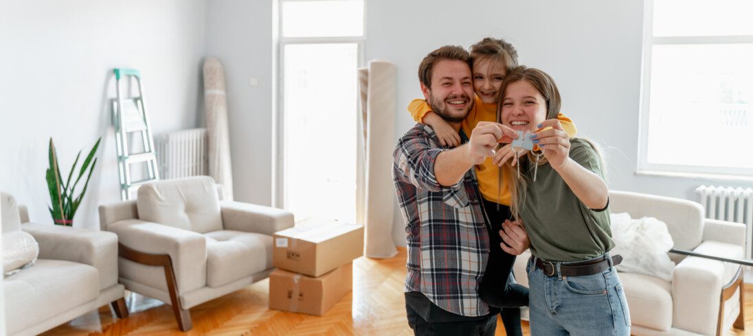 Foto que ilustra matéria sobre mercado imobiliário 2023 mostra um casal com um filho em uma sala de mudança