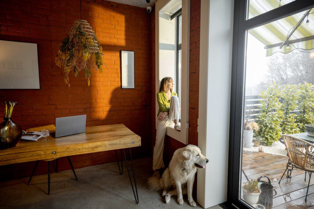 Menina apoiada na janela ao lado do seu cachorro, em um apartamento estilo garden.