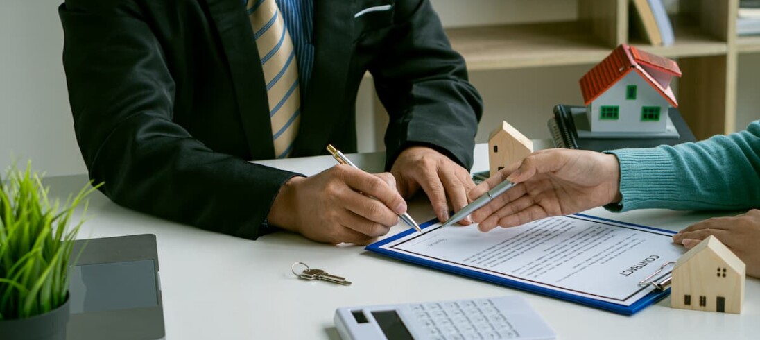 Um homem e uma mulher assinam um contrato de financiamento imobiliário.