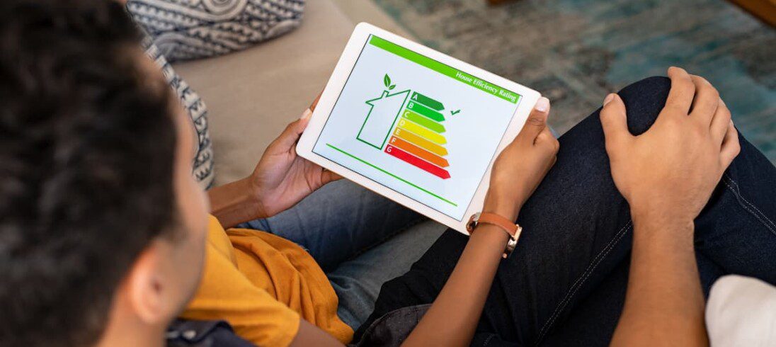 Um homem e uma mulher analisam, com auxílio de um tablet, a eficiência energética da casa.