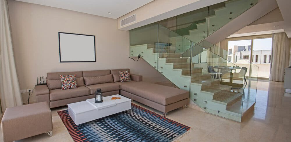 Foto que ilustra matéria sobre apartamento duplex mostra uma sala com uma escada que sobe para o segundo andar do imóvel ao fundo.