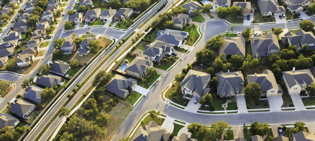 Imagem aérea de um bairro residencial com vista para os telhados das casas e as árvores próximas ao local para ilustrar matéria sobre os tipos de bairros de uma cidade