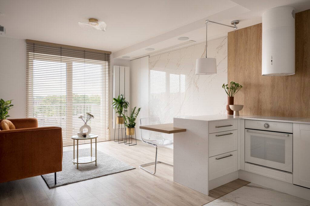 Imagem do interior de um apartamento elegante com uma janela grande e uma sala de estar simples com integração com a cozinha