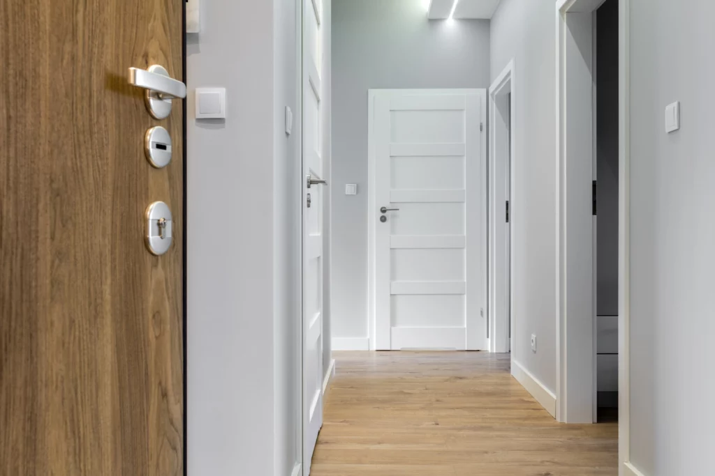 Imagem de Corredor com 3 portas e piso de madeira em apartamento moderno para ilustrar matéria sobre quanto custa um apartamento de 2 quartos