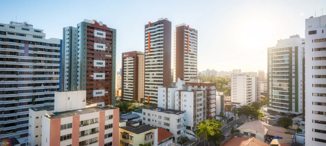 Imagem panorâmica de prédios de diversas alturas e cores em um dia ensolarado para ilustrar matéria sobre quanto custa um apartamento de 2 quartos