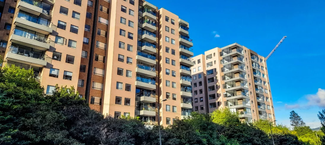 Imagem de três edifícios residenciais com avenidas bem arborizadas e céu azul para ilustrar matéria sobre como escolher o andar do apartamento