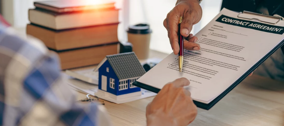 Imagem de um homem entregando uma prancheta com documento e uma caneta para outro homem vestido de azul para ilustrar matéria sobre declaração de residência para inquilino
