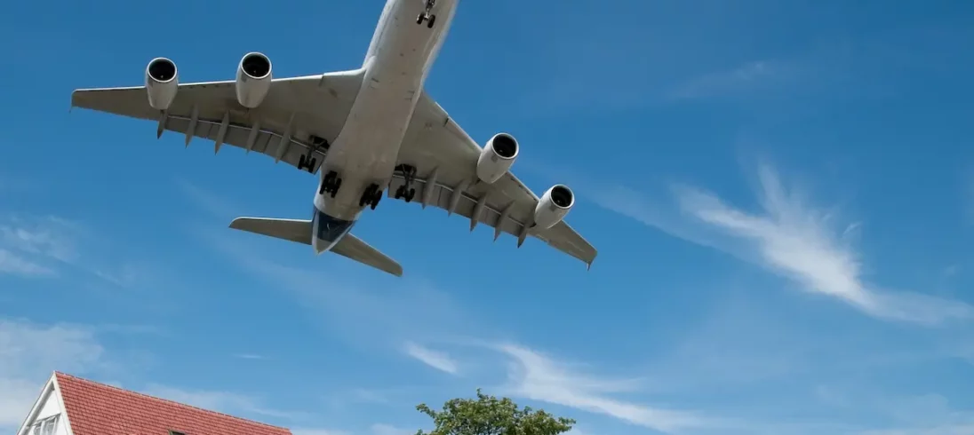 Avião passa por cima de uma casa próxima a um aeroporto.
