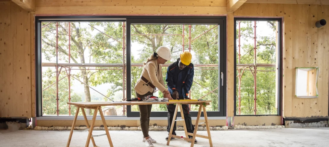 Imagem de dois trabalhadores do ramo de construção olhando plantas dentro de um imóvel para ilustrar matéria sobre construir para vender
