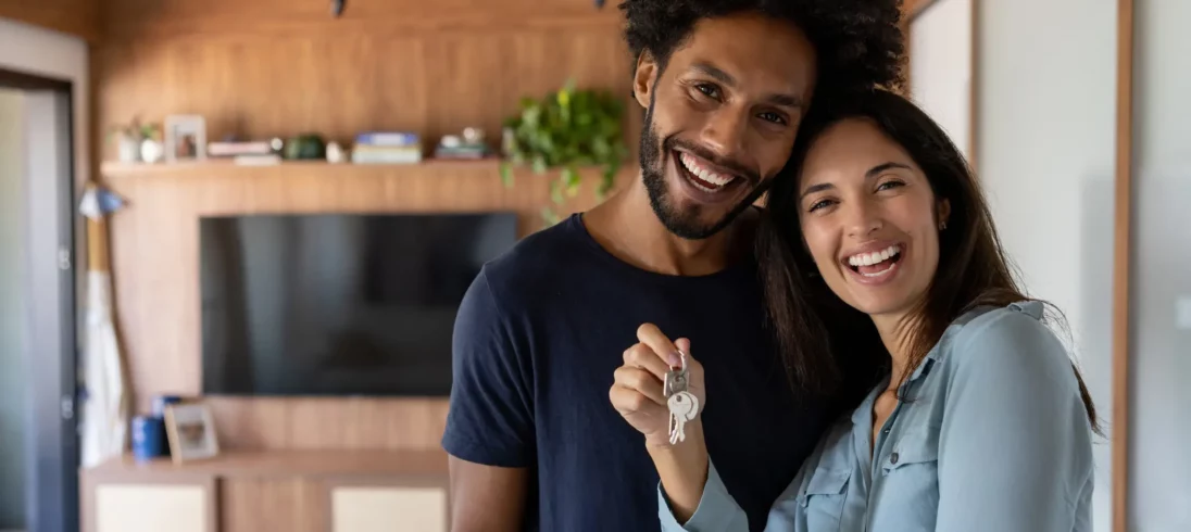 Foto de um casal feliz segurando a chave da casa nova.