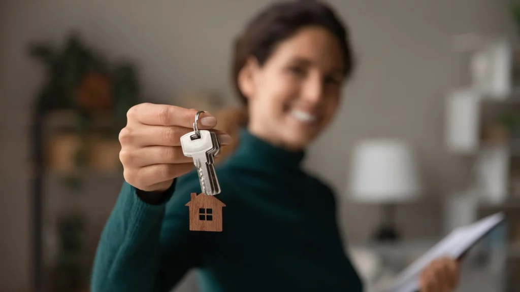 Imagem de uma mulher segurando a chave de um imóvel para ilustrar matéria sobre quem pode ser fiador de aluguel

