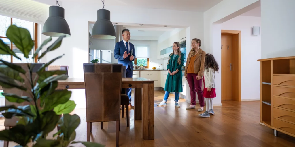 Imagem de um agente imobiliário mostrando um apartamento para uma família para ilustrar matéria sobre tamanho de apartamento