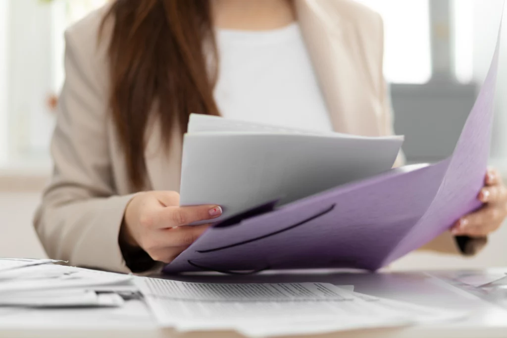 Imagem de uma mulher segurando documentos sentada à mesa  para ilustrar matéria sobre os documentos necessários para comprovar renda no consórcio