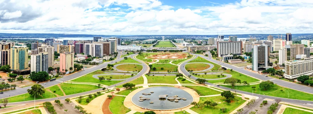 Imagem da paisagem urbana de Brasília mostra prédios, vegetação e céu azul