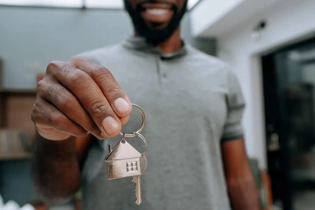 Imagem de um homem sorridente segurando as chaves de um imóvel para ilustrar matéria sobre se é possível viver da renda de aluguel
