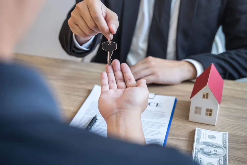 Imagem de uma pessoa de terno e gravata entregando uma chave a outra pessoa para ilustrar matéria sobre documentação para alugar imóvel