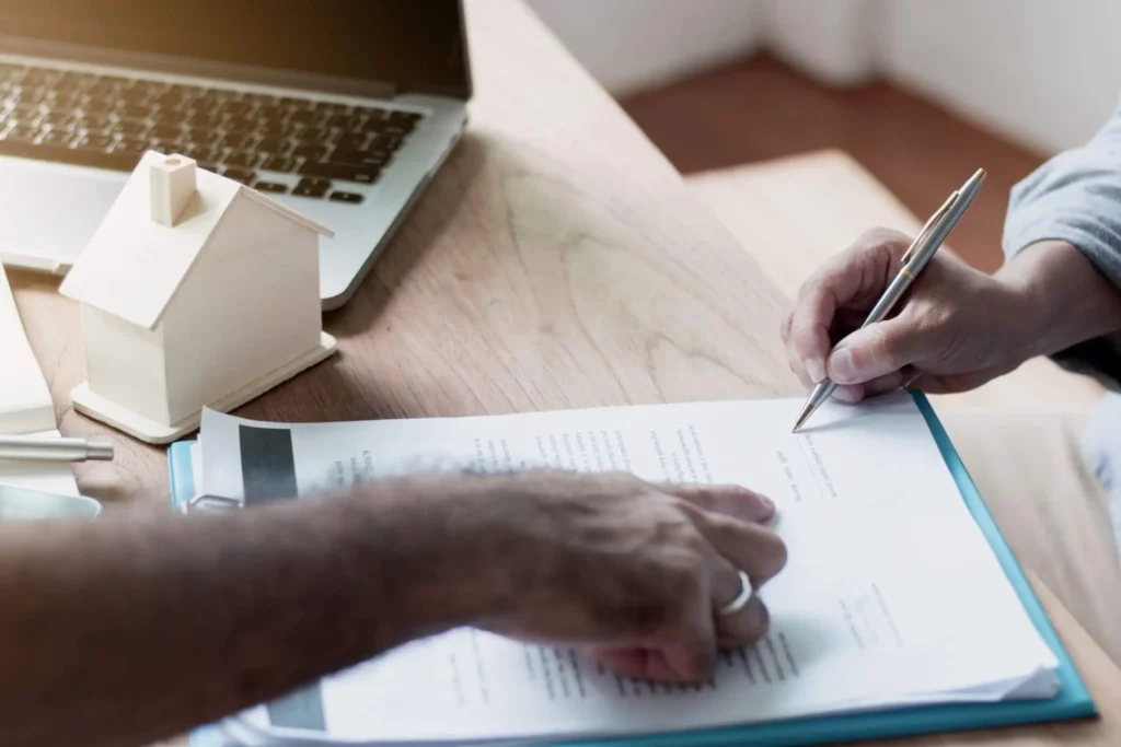 Imagem de uma pessoa apontando para uma folha de papel enquanto outra pessoa assina para ilustrar matéria sobre documentos para alugar imóvel