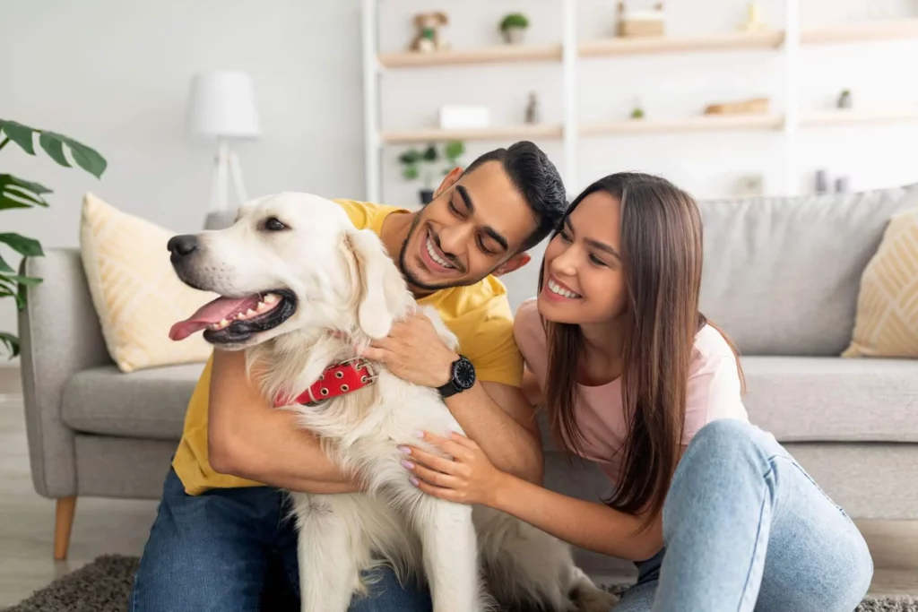 Imagem de um homem, uma mulher e um cachorro sentados na sala de uma casa para ilustrar matéria sobre o que está incluso no valor do condomínio 