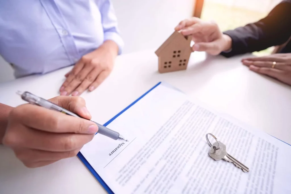 Imagem de uma pessoa assinando o contrato de aluguel na presença de um agente imobiliário para ilustrar matéria sobre se pode alugar imóvel financiado pelo Minha Casa, Minha Vida