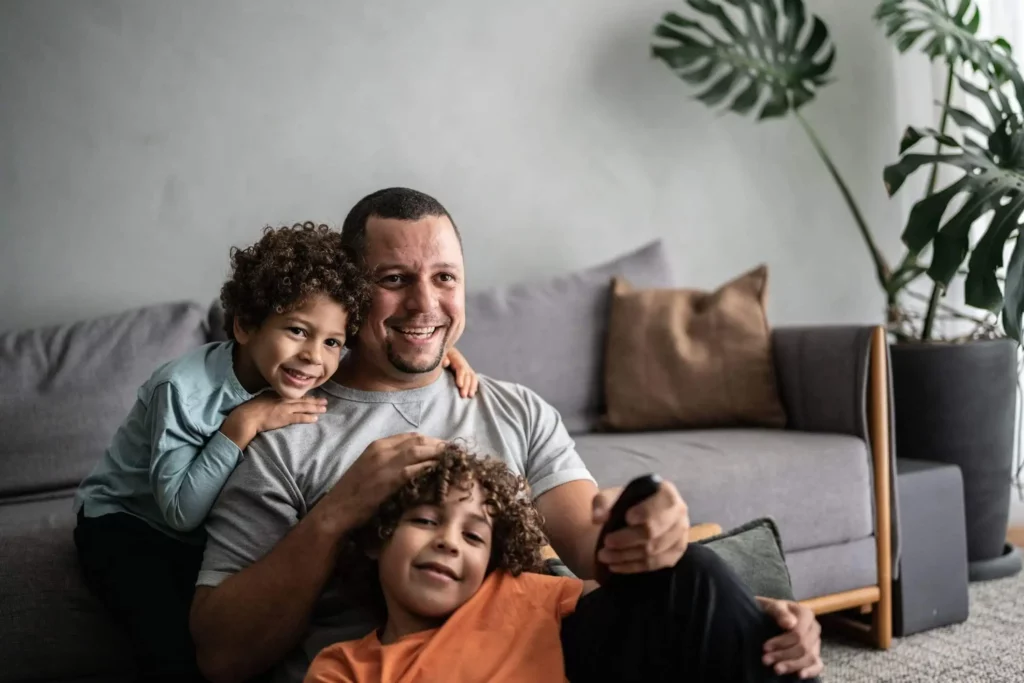 Imagem de um pai com dois filhos pequenos sentados no chão da sala de estar para ilustrar matéria sobre o que é IGP-M do imóvel